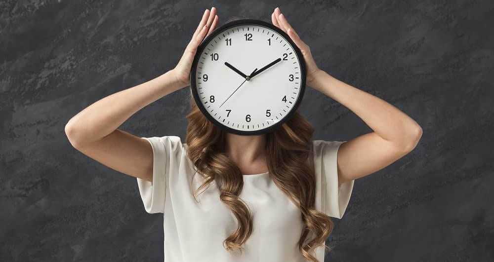 Женщина закрывает голову большими часами